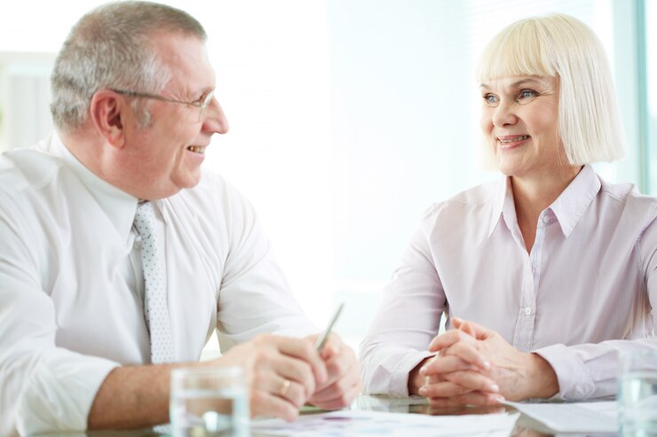 Senior couple discussing reverse mortgages with a financial advisor, representing financial planning for elderly care.